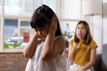 Indoor shot of young Asian girl crying and cover her ear with hands and feel sad while get scold...