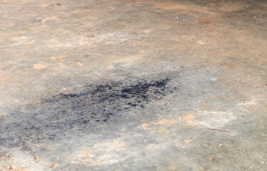 Black soot or oil slick from car exhaust pipe droping on dirty cement or concrete floor in old garage
