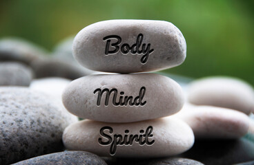 Body, Mind and Spirit words engraved on zen stones. Copy space and zen concept