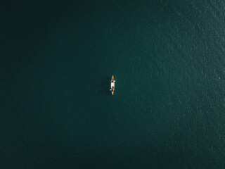 small canoe seen from a great height alone with two people inside in the middle of the lake areas...