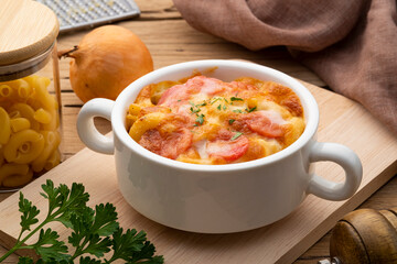 Baked macaroni with sausage and cheese with fresh parsley leaves in white bowl