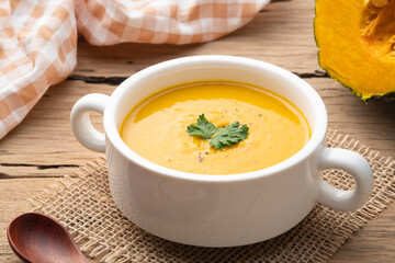 pumpkin carrot cream soup in white bowl,garnished with parsley.Healthy food - Powered by Adobe