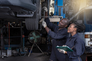 Obraz na płótnie Canvas Black African man and woman mechanics fixing car in auto repair shop, Car Maintenance Concept