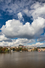 Fototapeta na wymiar View over Vltava river to Charles bridge, Prague Castle in background under blus sky with white clouds.