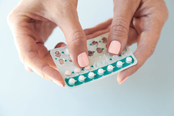 Women's hands hold contraceptive pills. The topic of women's health. Taking a pill.