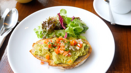 Healthy breakfast with avocado on sliced bread with tomatoes in cafe