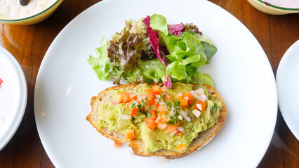 Healthy vegan breakfast in cafe with avocado toast on plate