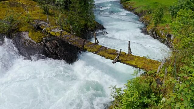 wooden bridge across Lake Lovatnet with a glacial river, view from above. moving aerial