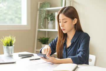 Account finance, asian young business woman hand use calculator for calculate budget, cost and income of company from charts, reports paperwork, plan spend money expenses, working on desk at home.