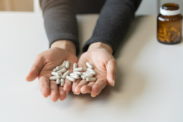 Anti drugs, drug addict, asian young woman hand pour, holding bulk medicine out of pills bottle on table at home, abuse overdose. Sick pain of health, unhealthy people. Suicide depressed or despair.