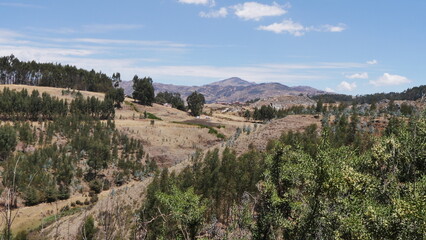 Fototapeta na wymiar Un parc national péruvien naturel et bien entretenu, avec plaines, chemins de terre, montagnes rouges, petites forêts, sous un soleil de plomb, balade bien-être, parcours sportif