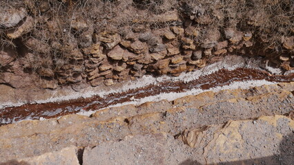 Petit ruisseau laissant couler du sel sur les bords, de l'eau sortant de la montagne, formation de bloc avec du sable, entre des murets de pierre historique