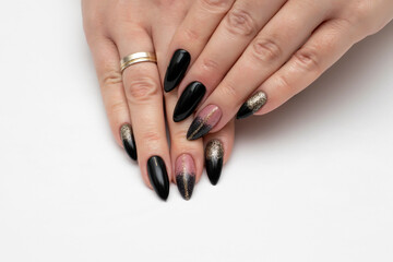 Black beige manicure with gold glitter and a gold stripe. Long sharp nails on a white background close-up.