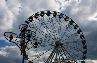 A new metal Ferris wheel with booths on the background of a blue cloudy sky in Vladimir Park Russia on a summer day and a space for copying