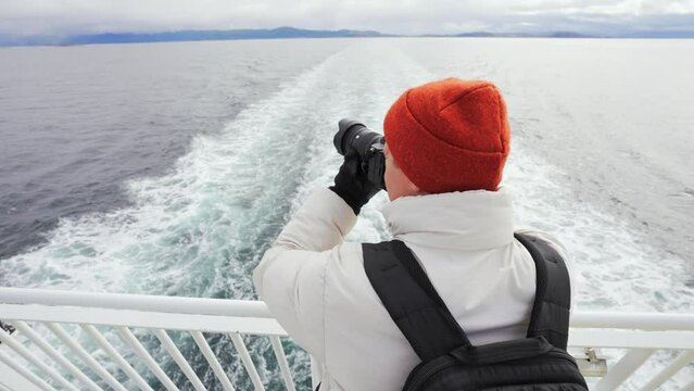 Young Man on a Ferry Taking Panorama Photo of Sea with DSLR camera