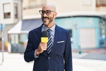 Young hispanic man reporter working using microphone at street