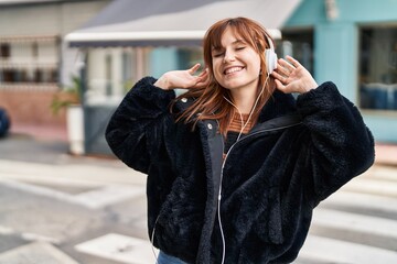 Young woman listening to music and dancing at street