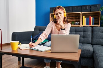 Young caucasian woman working using computer laptop serious face thinking about question with hand on chin, thoughtful about confusing idea