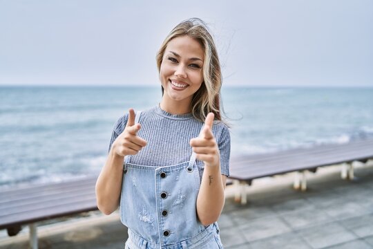 Young caucasian woman outdoors pointing fingers to camera with happy and funny face. good energy and vibes.