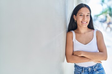 Young beautiful hispanic woman standing with arms crossed gesture at street