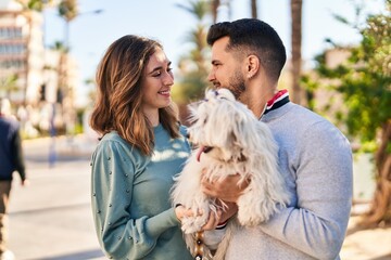 Man and woman holding dog standing together at park