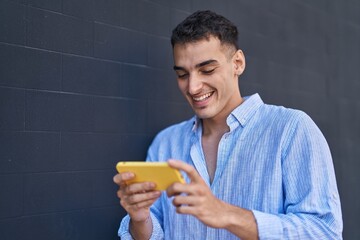Young hispanic man smiling confident watching video on smartphone over black isolated background