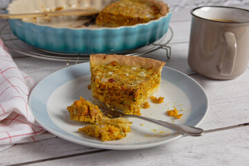 Close up of a piece of pumpkin quiche served on a plate.