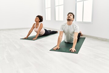 Young african american woman and hispanic man exercising at pilates room, stretching body and doing yoga pose, training strength and balance