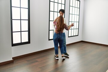 Fototapeta na wymiar Young hispanic couple smiling happy dancing at empty new home.