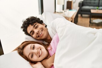 Fototapeta premium Young couple smiling happy and hugging lying on the bed at bedroom.