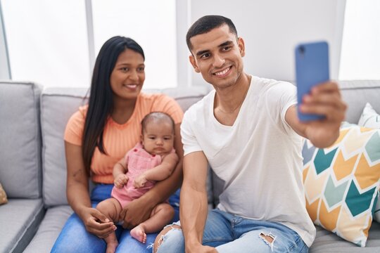 Hispanic family using smartphone sitting on sofa at home