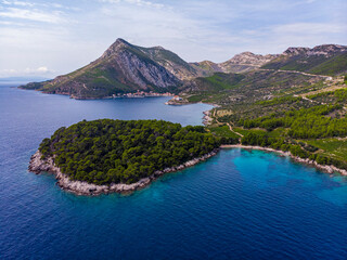 aerial view of a wonderful Mediterranean bay on the peljesac peninsula; paradise beach with turquoise water and rocky coastline with mighty mountains in the background; trstenik in croatia