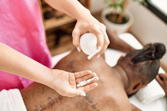 Young african american man having back massage with cream lotion at beauty center