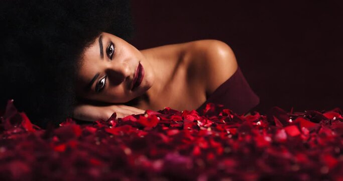 Fashion model, face or petals from red rose on studio table of Ethiopian woman and lipstick makeup cosmetics. Portrait, beauty person or flowers in creative luxury art of feminine romance empowerment