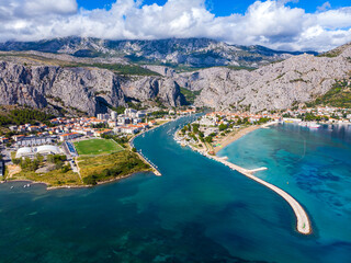 Obraz premium aerial view of the town of omiš in croatia, a picturesque town on the adriatic coast with the mouth of the cetina river, a beautiful beach and mighty mountains in the background as seen from a drone