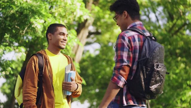 Two young black men giving high five and walking to university, students life