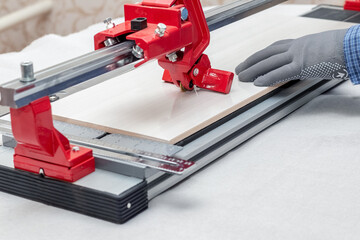 A worker cuts facing tiles with a tile cutter