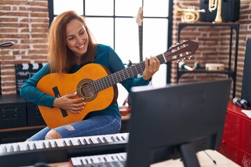 Fototapeta na wymiar Young woman musician playing classical guitar at music studio
