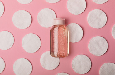 Micellar cleansing water and cotton pads on a pink background, top view. Place for text. Flat...