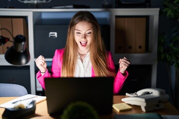 Young caucasian woman working at the office at night celebrating surprised and amazed for success with arms raised and open eyes. winner concept.