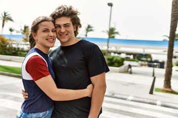 Young caucasian couple smiling happy and hugging at the city.