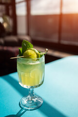 yellow alcohol cocktail with lime, mint, ginger, honey on table, bar, restaurant