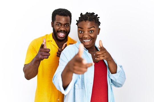 Young african american couple wearing casual clothes pointing fingers to camera with happy and funny face. good energy and vibes.