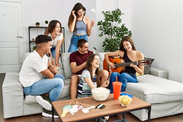 Group of young friends having party playing classical guitar at home.