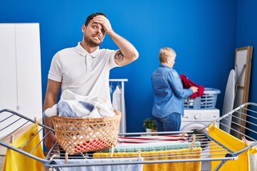 Hispanic mother and son hanging clothes at clothesline stressed and frustrated with hand on head, surprised and angry face