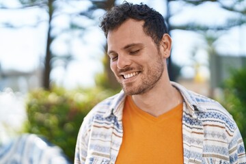 Young hispanic man smiling confident standing at park