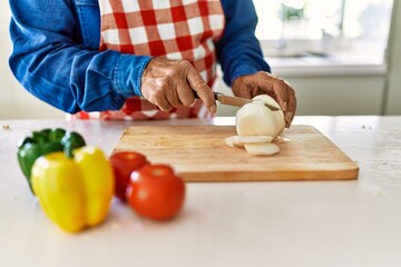 Obraz na płótnie Canvas Senior man cutting onion at kitchen