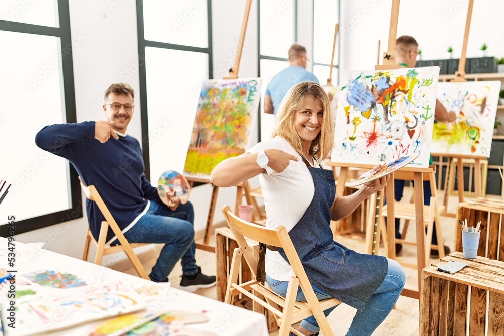 Wall mural Group of middle age artist at art studio looking confident with smile on face, pointing oneself with fingers proud and happy.