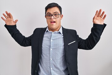 Young hispanic man with down syndrome wearing business style celebrating crazy and amazed for success with arms raised and open eyes screaming excited. winner concept