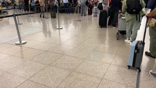 people waiting queuing up with their travel luggage at airport check-in